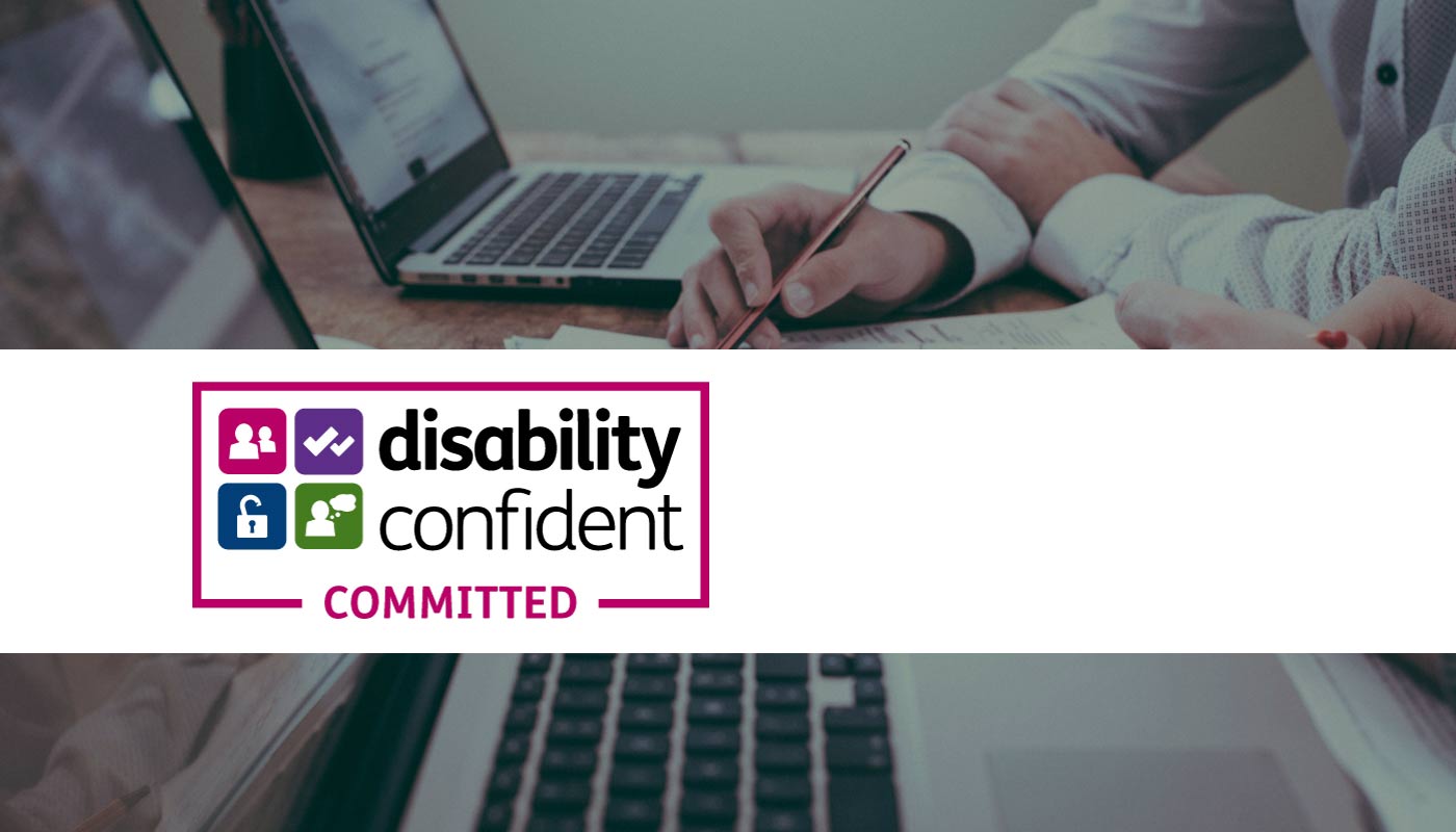 Image of person signing paperwork overlaid with the Disability Confident Committed logo